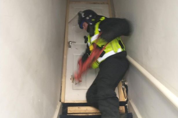 A police officer uses a ram to smash the door of the property