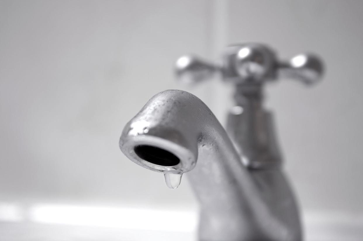 Close-up of water drop on domestic chrome faucet, shallow depth of field, water conservation concept.