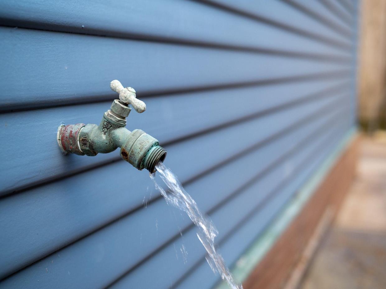 Water flows from the outside garden hose faucet outside the house