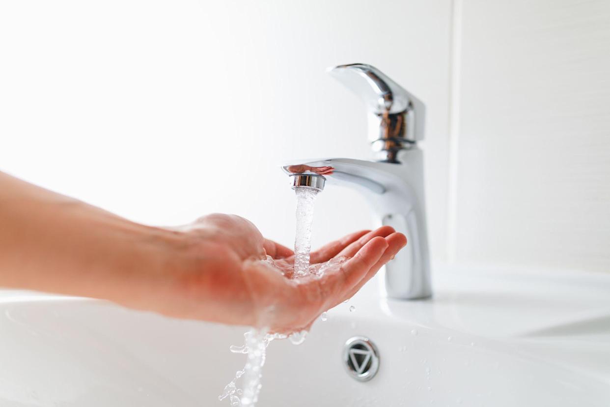 hand under the tap with water flow, close-up view