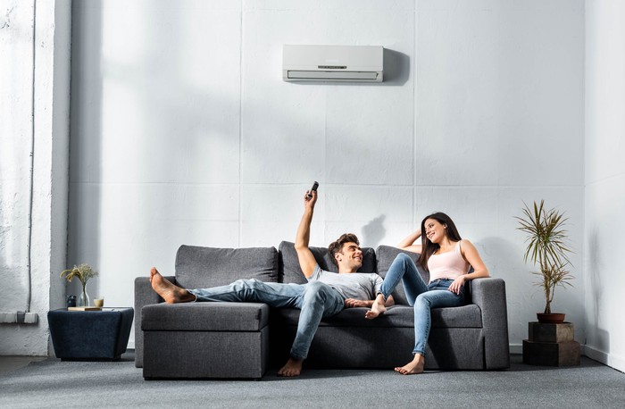 A couple using air conditioning while relaxing on a sofa in the living room.