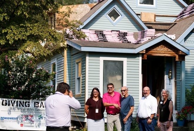 Ronald Burger shakes hands with Owens Corning Representative Ken Adler (in pink) as they pose for a photo with representatives from Habitat for Humanity of Springfield and Catholic Charities of Southern Missouri before Burger gets a new roof on his home as part of Owens Corning Roof Implementation Project.