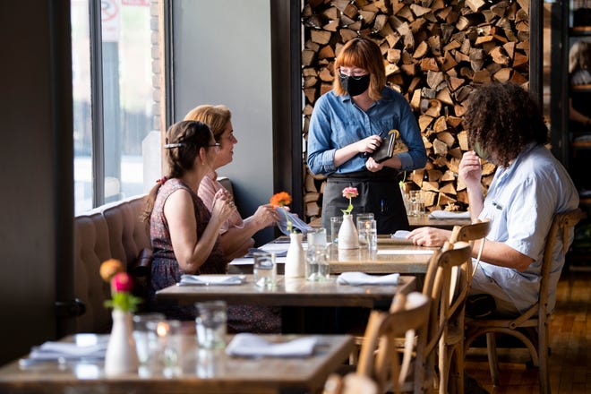 Server Kelsey Bledsoe, who is in the center, is taking the order for a table at JC Holdway in downtown Knoxville on Thursday. The restaurant has reopened for the first time in two months after water from the fire suppression system damaged the drywall and floors.
